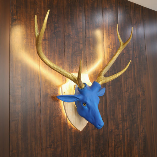Blue deer head with gold antlers mounted on a wooden wall.